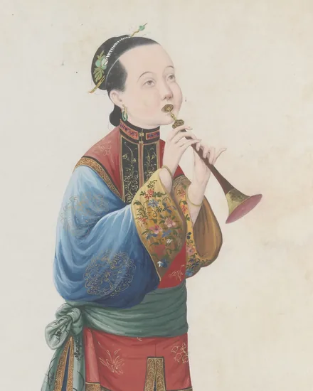 A woman in a blue robe with an embroidered red-and-gold jacket and green sash stands playing a suona, its slender wooden body and flared brass bell raised to her lips.